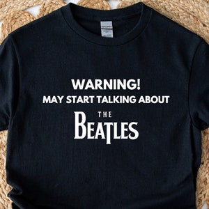 May include: Black t-shirt with white text that reads "WARNING! MAY START TALKING ABOUT THE BEATLES".