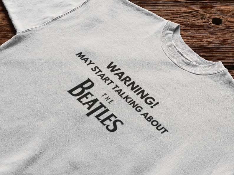 May include: A gray t-shirt with black text that reads "WARNING! MAY START TALKING ABOUT THE BEATLES".