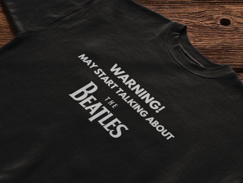 May include: Black t-shirt with white text that reads "WARNING! MAY START TALKING ABOUT THE BEATLES".