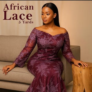 May include: A burgundy off-the-shoulder dress with detailed floral lace. The dress features long sleeves and a fitted shape. Text in the upper left corner reads "African Lace 5 Yards".