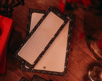 Puede incluir: Dos cuadernos con patrones en blanco y negro con páginas en blanco. Los cuadernos están sobre una superficie de madera con un libro rojo, una vela y cartas de tarot.