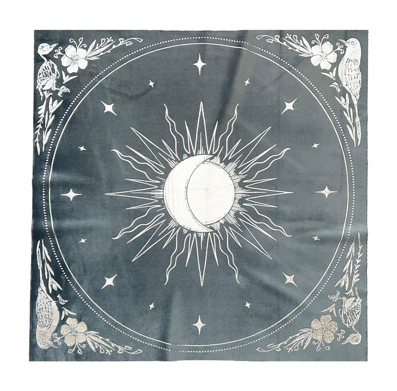 Pu&ograve; includere: Un arazzo grigio con un design di sole e luna bianco. Il sole ha raggi e la luna &egrave; una mezzaluna. L'arazzo &egrave; circondato da un bordo floreale bianco con uccelli.