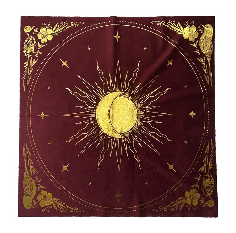 Pu&ograve; includere: Un arazzo quadrato color borgogna con un designo di sole e luna dorati. Il sole e la luna sono circondati da un cerchio di stelle dorate. L'arazzo ha un bordo floreale dorato con uccelli.