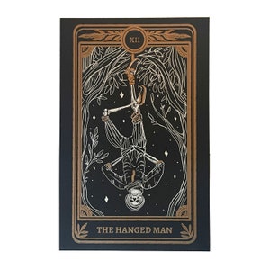 the hanged man tarot print on altar with altar cloth, skull, and candle. Design from the Marigold Tarot deck