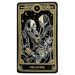 May include: Black and gold embroidered patch featuring the Lovers tarot card. The card depicts two skeletons in robes, holding hands and looking at each other. The card number VI is in a gold circle at the top of the card.