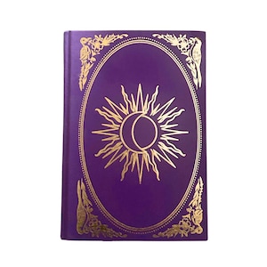 Peut inclure: Un journal violet avec un motif de soleil et de lune doré dans un cadre ovale. La couverture présente des coins floraux dorés et une bordure dorée. Le journal est fermé et de forme rectangulaire.