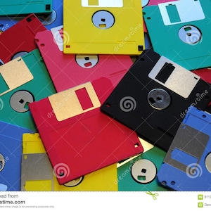 May include: A pile of colorful floppy disks in various shades of blue, green, red, yellow, and black. The disks are arranged in a random pattern, with some overlapping.