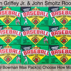 May include: Nine 1989 Bowman baseball wax packs. Each pack is green with red and white text, featuring the word "BASEBALL" and the Bowman logo. The packs include 12 picture cards and 1 stick of bubble gum. Text at the top reads "Ken Griffey Jr. & John Smoltz Rookie."
