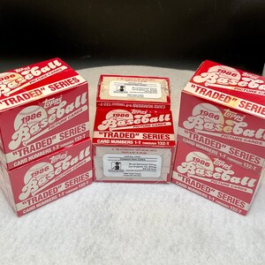 May include: Three unopened boxes of 1986 Topps "Traded" Series Baseball cards. The boxes are red and white with the Topps logo and the words "1986 Topps Baseball" and "Traded Series".