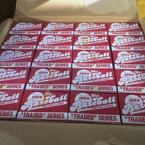 May include: A box filled with 1986 Topps Baseball cards, all in their original packaging. The boxes are red with white lettering and feature the Topps logo and the words "1986 Baseball Picture Cards" and "Traded Series".