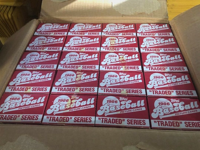 May include: A box filled with 1986 Topps Baseball cards, all in their original packaging. The boxes are red with white lettering and feature the Topps logo and the words "1986 Baseball Picture Cards" and "Traded Series".