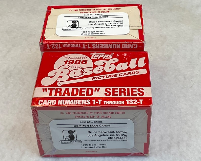 May include: Two red and white cardboard boxes of 1986 Topps Traded Baseball cards. The boxes are sealed and feature the Topps logo, the year 1986, and the text "Traded" series. The boxes also include the card numbers 1-T through 132-T.