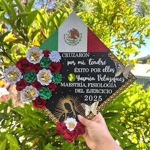 May include: A graduation cap decorated with a Mexican flag design, flowers, and text. The cap features red, white, and green colors, with the Mexican coat of arms. Text includes the name "Yasmin Velázquez" and the year "2025".