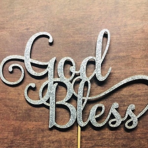 May include: Silver glitter cake topper with the words "God Bless" in a cursive font.