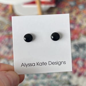 May include: A pair of black stud earrings on a white card with the text "Alyssa Kate Designs".