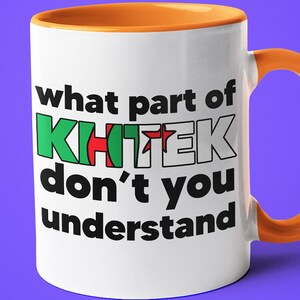 Peut inclure: Une tasse en céramique blanche avec un bord et une poignée orange. La tasse porte une inscription noire qui dit "what part of KHITEK don't you understand".