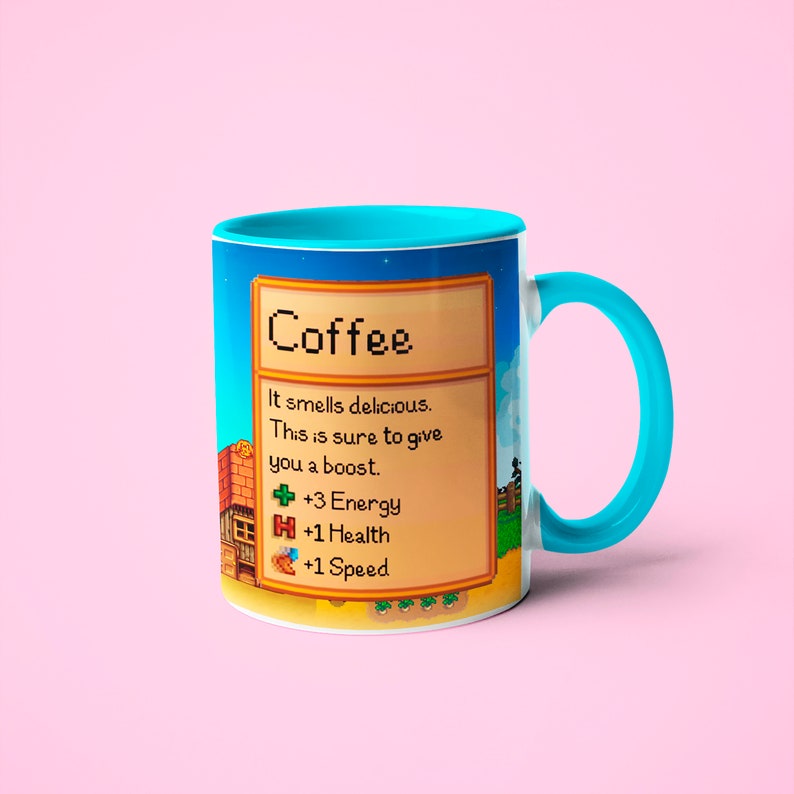 May include: A white coffee mug with a blue rim and handle. The mug features a pixelated image of a coffee item from a video game with the text "Coffee" and a description of its effects: "It smells delicious. This is sure to give you a boost. +3 Energy +1 Health +1 Speed"