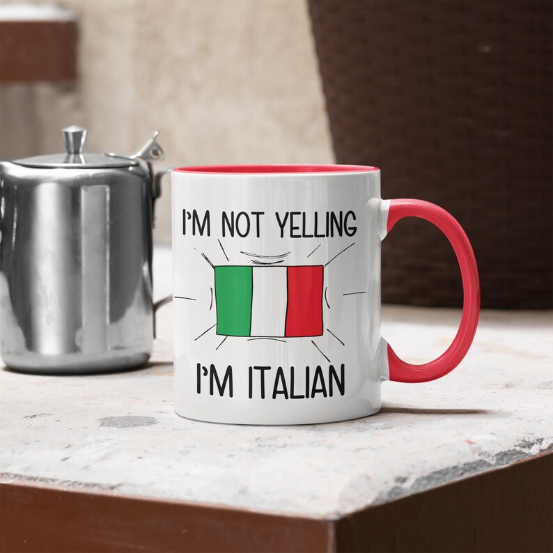 May include: White ceramic mug with a red rim and handle. The mug has a black graphic that says "I'm not yelling I'm Italian" with a cartoon drawing of the Italian flag.
