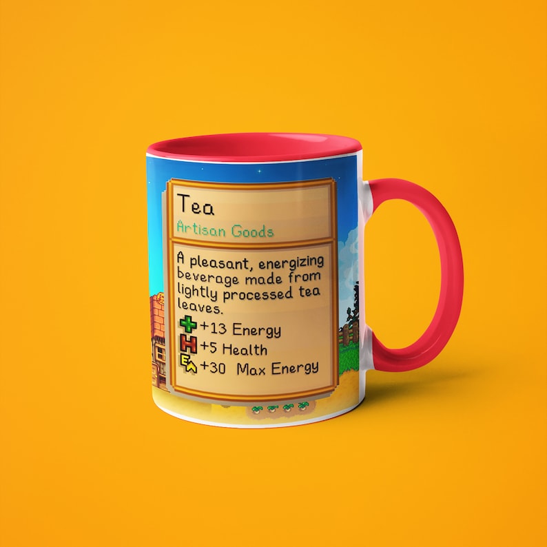 Op de afbeelding: Een witte keramische mok met een rode rand en handvat. De mok heeft een gepixelde afbeelding van een videospel-itemkaart met de tekst "Tea Artisan Goods" en statistieken voor energie, gezondheid en maximale energie.