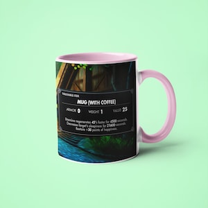 May include: A pink and white ceramic mug with a video game-style graphic. The mug features a dark background with a small wooden house and a river. The text on the mug reads "VALUABLE ITEM MUG (WITH COFFEE) ARMOR 0 WEIGHT 1 VALUE 25 Stamina regenerates 45% faster for 4500 seconds. Decrease target's sleepiness for 21600 seconds. Restore +30 points of happiness."