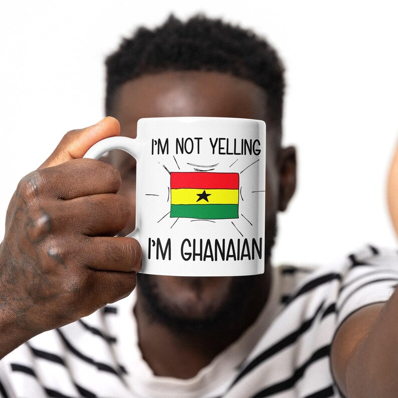 May include: White ceramic mug with a black and red design. The mug has the text "I'm not yelling I'm Ghanaian" and a cartoon image of the Ghanaian flag.