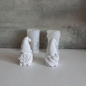 Könnte beinhalten: Weiße Zwergfiguren mit langen Hüten und Bärten, eine hält eine Schneeflocke. Zwei zylindrische Formen befinden sich hinter den Figuren. Die Zwerge sind wahrscheinlich für Weihnachtsdekoration oder Bastelarbeiten.