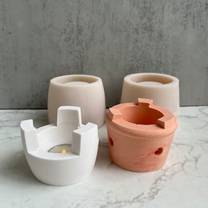 Può includere: Quattro stampi in silicone per realizzare portacandele in cemento. Due stampi sono bianchi e due sono pesca. Uno stampo bianco è a forma di portacandele tradizionale con quattro gambe. L'altro stampo bianco è un semplice cilindro. Gli stampi pesca sono entrambi a forma di portacandele tradizionali con quattro gambe.