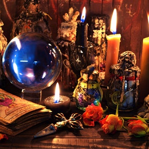 Könnte beinhalten: Eine mystische Szene mit einer großen, leuchtenden blauen Kristallkugel, brennenden Kerzen und einem Tarotkartendeck. Die Anordnung umfasst verschiedene Flaschen, getrocknete Rosen und einen dekorativen Dolch, wodurch eine thematische Atmosphäre entsteht.