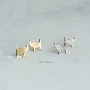 May include: Two pairs of cat-shaped stud earrings. One pair is gold and the other is silver.