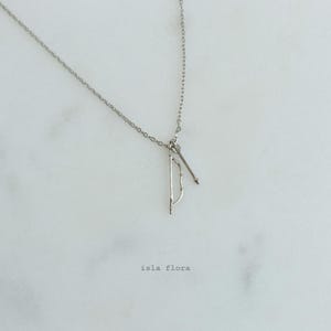 May include: A silver necklace with a bow and arrow charm. The charm is a simple design with a thin bow and arrow.