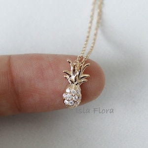 Peut inclure: Collier en or en forme d'ananas avec des accents de cristal transparent. Le collier est sur une chaîne délicate et est un petit bijou délicat.