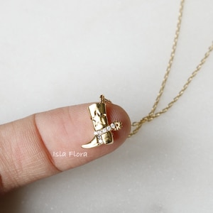 May include: A gold necklace with a boot charm. The boot is decorated with small clear stones.