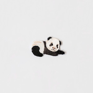 Peut inclure: Un patch brodé représentant un panda noir et blanc. Le panda est couché sur le côté, la tête tournée.