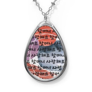 May include: A silver chain necklace with a teardrop-shaped pendant. The pendant features a colorful abstract design with Korean text that reads "할머니 사랑해요" which translates to "I love you, grandma".