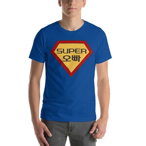 May include: A royal blue t-shirt with a red and yellow superhero logo. The logo says "SUPER" in black letters and "오빠" in Korean letters.