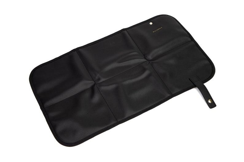 May include: Black changing mat with a fold-over design and a small strap. The mat has five sections and is made of a water-resistant material.