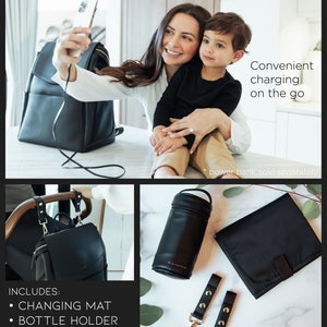 May include: A black diaper bag with a USB charging port, a changing mat, a bottle holder, stroller straps, and a purse strap. The bag is shown on a white surface with a woman and child in the background.