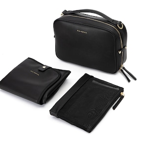 May include: A black leather diaper bag with gold hardware and a matching changing mat and zippered pouch. The bag has a top handle and a shoulder strap.