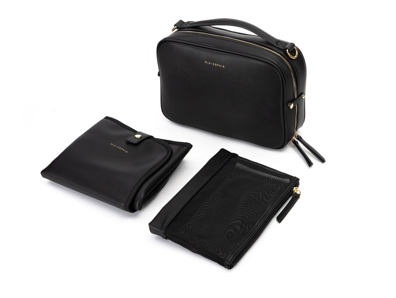 May include: A black leather diaper bag with gold hardware and a matching changing mat and zippered pouch. The bag has a top handle and a shoulder strap.