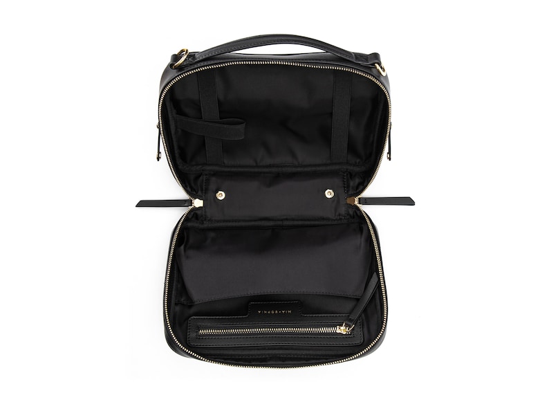 May include: Black leather travel makeup bag with gold hardware and a zipper closure. The bag is open and the interior is visible.