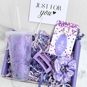 Pu&ograve; includere: Una confezione regalo contenente un bicchiere viola satinato con cannuccia, un portachiavi viola in stile motel con il nome Mia, una pinza per capelli viola e un elastico in raso viola. Un biglietto riporta la scritta JUST FOR you.