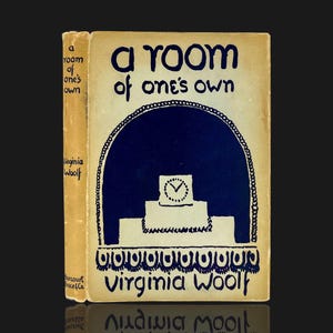 May include: A vintage book titled "A Room of One's Own" by Virginia Woolf. The cover is cream-colored with dark blue lettering and a graphic of a clock. The book's spine is visible, showing the title and author.