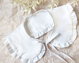 May include: White cotton collar with a ruffled edge and a tie fastening. The collar is made from a soft, lightweight fabric and is ideal for adding a touch of vintage style to any outfit.