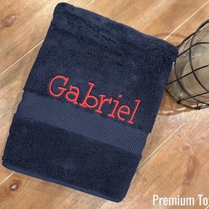 May include: A dark blue towel with a red embroidered name "Gabriel" on it. The towel has a textured border. Premium Towel.