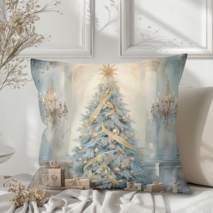 May include: A decorative square pillow featuring a watercolor painting of a Christmas tree. The tree is light blue with gold ornaments and ribbon. The pillow has a light blue and gold color scheme, with a star on top of the tree.