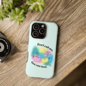 May include: A light mint green phone case featuring a central graphic of a creature relaxing in a bathtub surrounded by a colourful watercolour splash. The text Don't call me, You can text. is printed in black above and below the illustration.