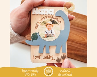 Könnte beinhalten: Ein Holzschild mit einem blauen Dinosaurier-Ausschnitt, einem Fotorahmen und dem Text "Nana Danke, dass du so toll bist! Liebe, James".