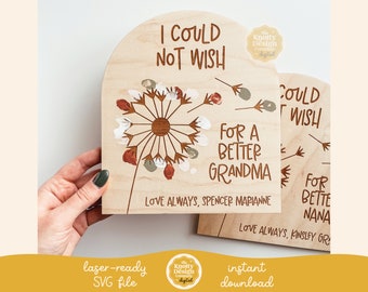 May include: Two wooden signs with a dandelion design and the text "I could not wish for a better grandma" and "I could not wish for a better nana". The signs are laser-cut and ready to be personalized.