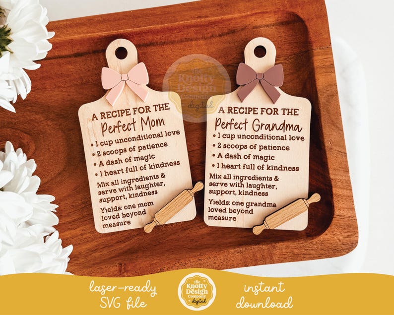 May include: Two wooden cutting board shaped plaques with text, each topped with a bow and a small rolling pin. One reads "A Recipe for the Perfect Mom" and the other "A Recipe for the Perfect Grandma". The plaques are on a wooden tray.