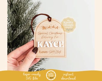 May include: A wooden Christmas ornament with a white background and brown text. The ornament says "Special Christmas Delivery For KAYCE Love: Santa Claus".